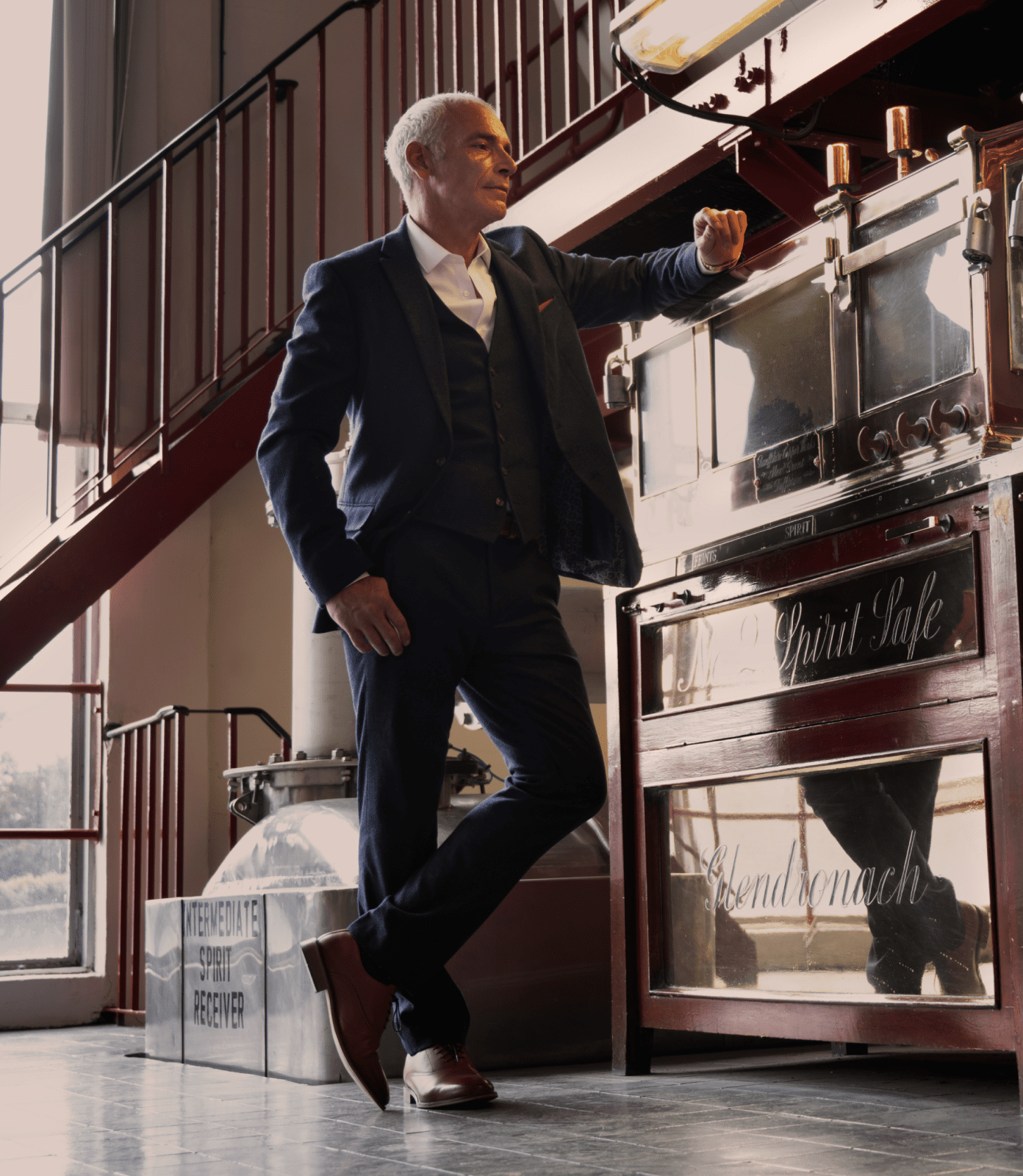Portrait of Stewart Buchanan leaning against distillery equipment.