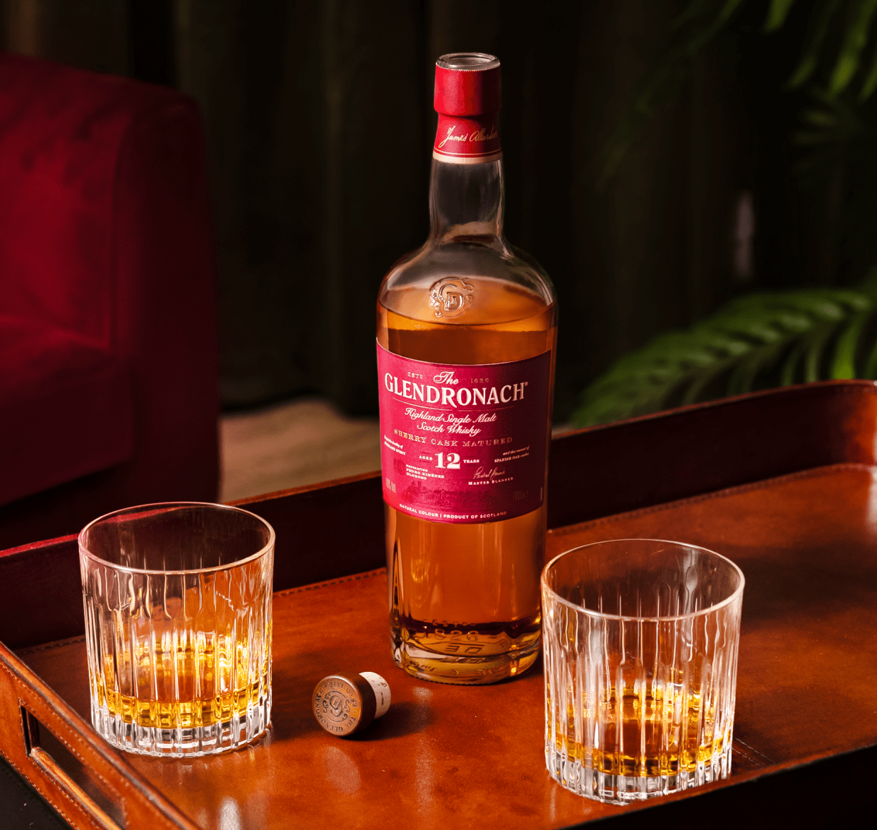 An image of The Glendronach Whisky, Aged 12 Years, bottle on a wooden serving tray with two crystal glasses sitting next to it.